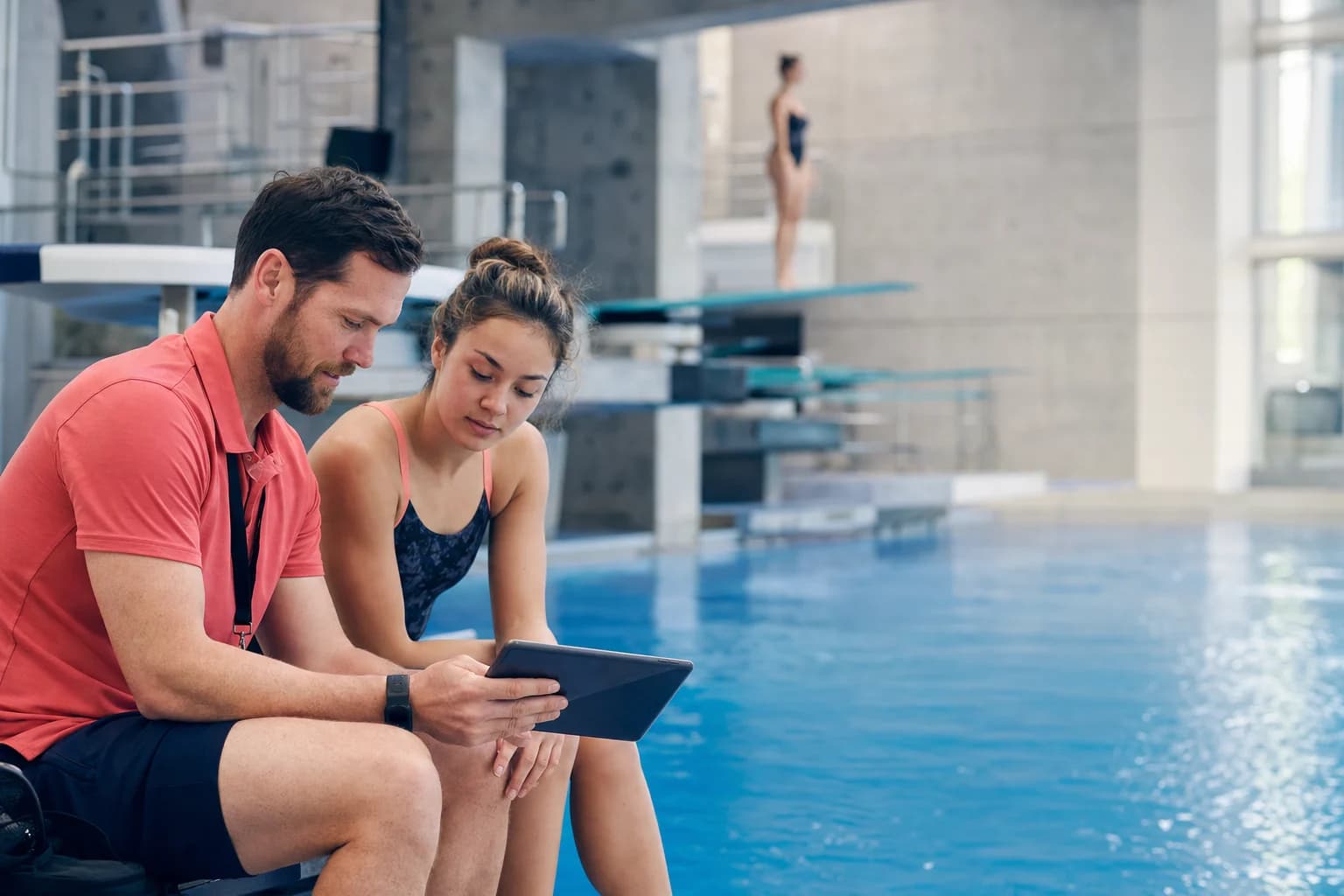 A college diving coach working with an athlete during practice
